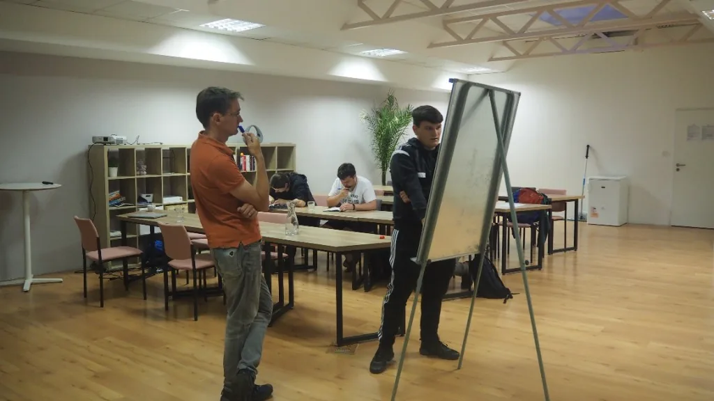 Lektor a uchazeč u flipchartu během cvičného pohovoru v učebně Turing Institutu
