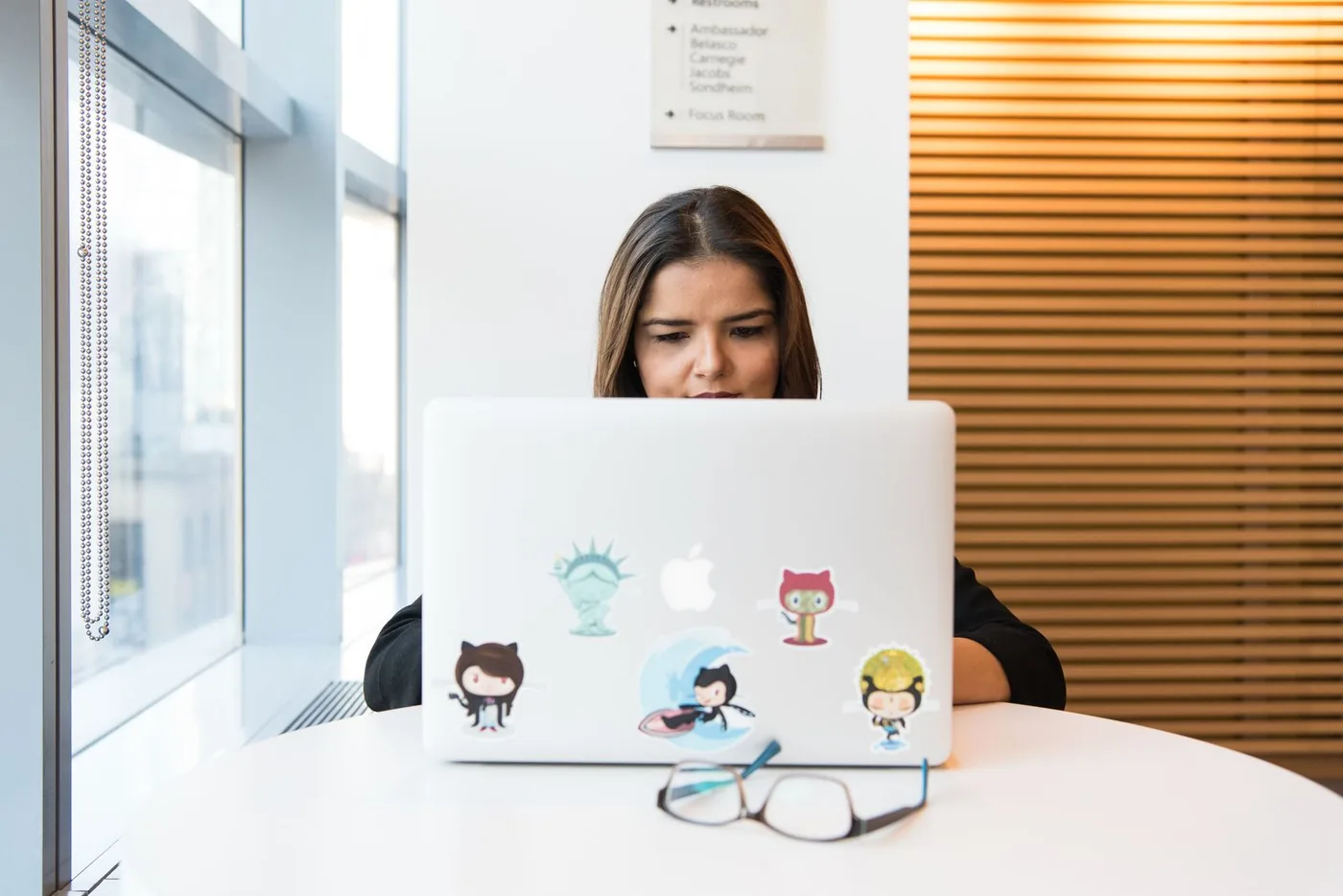 Vývojářka pracuje na notebooku polepeném samolepkami GitHub Octocat